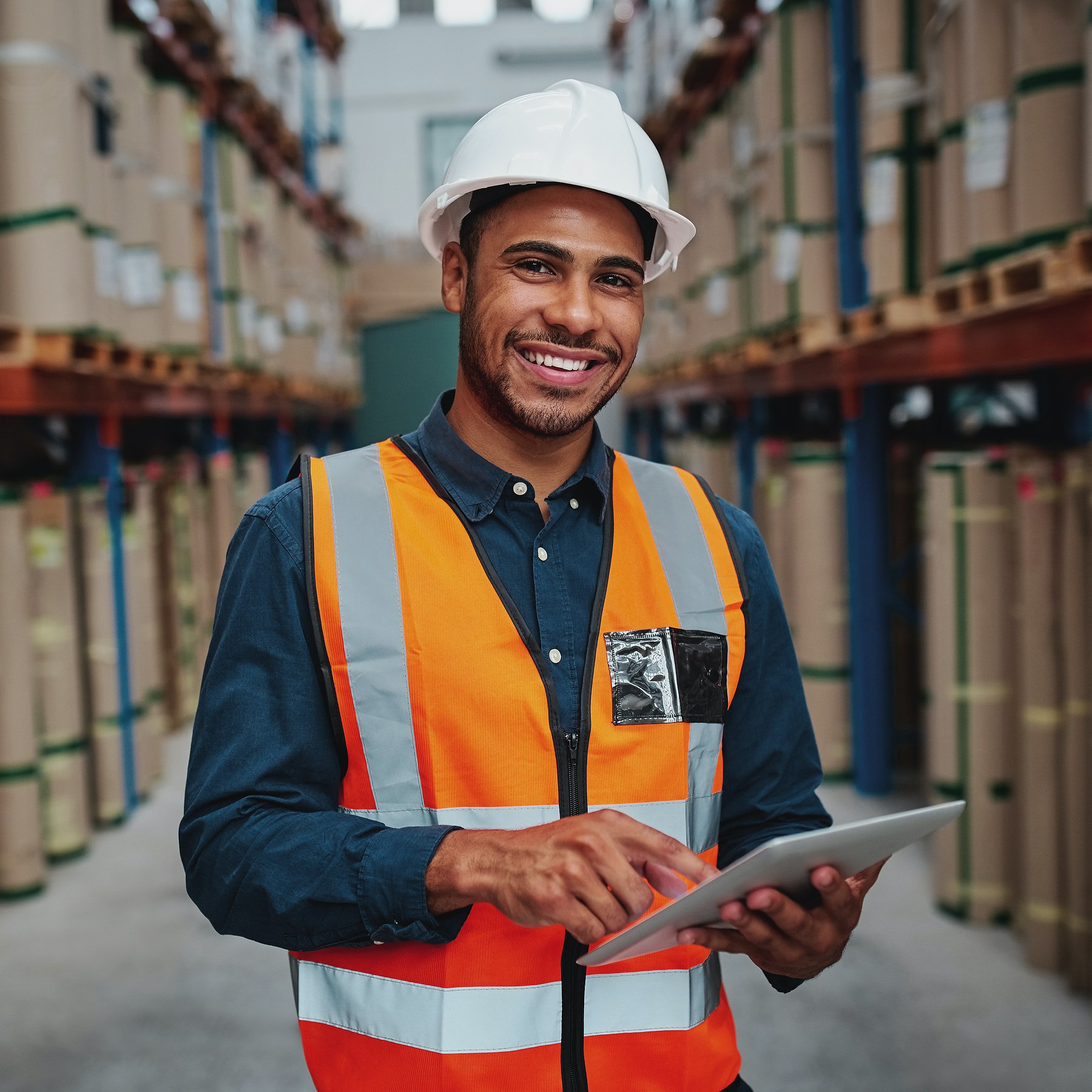 Happy Male Factory Manager Using Digital Tablet In Warehouse While Standing Against Goods Shelf Look